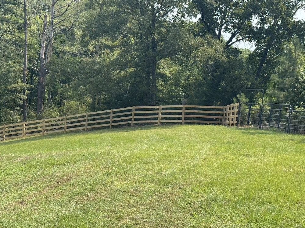 Request a free fence estimate — Masters Fence Co Birmingham, AL Four-rail wooden post and board horse fence across a Central Alabama field